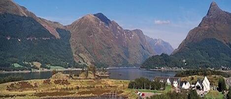A coastal landscape with mountains, a lake, and a small settlement with houses.