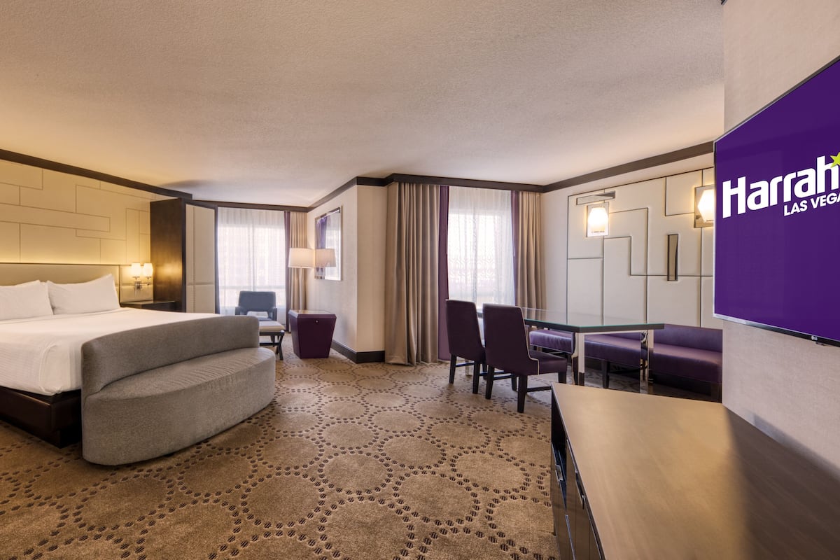 A hotel room with a large bed, a desk, and a seating area.