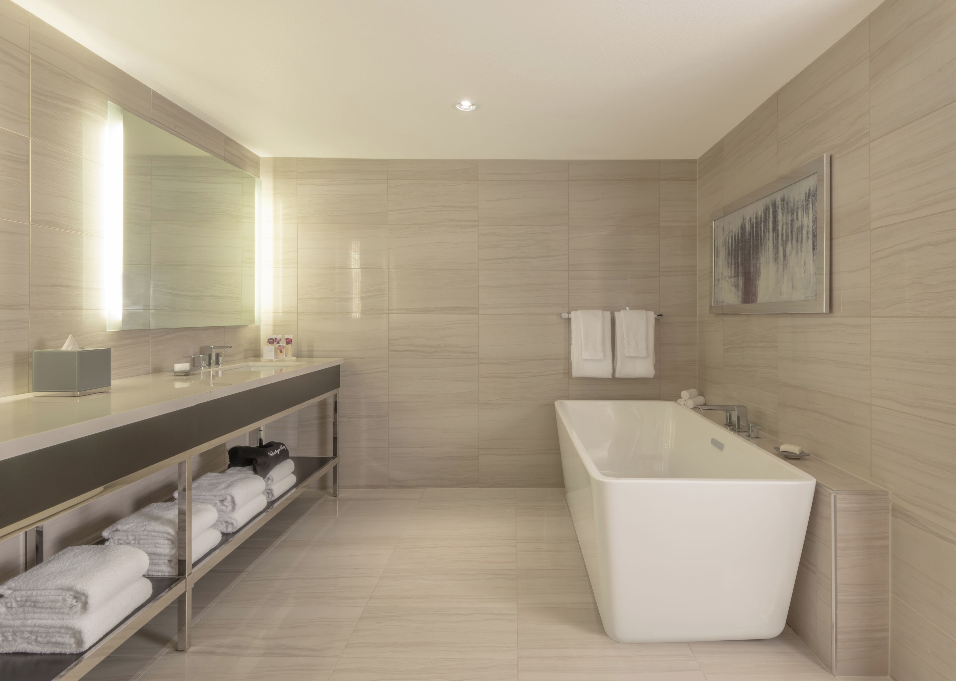 Une salle de bain moderne avec une grande baignoire, un meuble-lavabo avec un miroir et une étagère avec des serviettes.