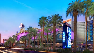 A brightly lit hotel with palm trees and neon signs.