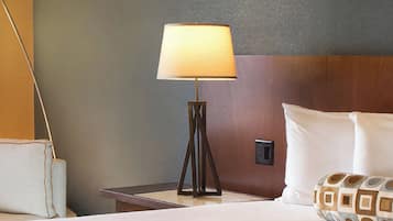 A hotel room with a bedside lamp, a bed with white bedding, and a nightstand.