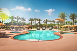 A pool area with multiple sun loungers and umbrellas, surrounded by palm trees. - Excalibur Hotel & Casino (Las Vegas)