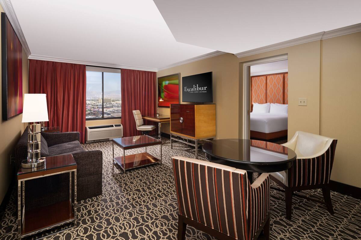 Een hotelkamer met een groot raam, een bed, een bureau, een stoel en een televisie.