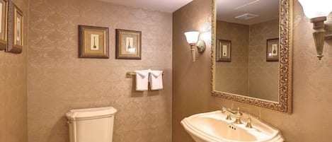 Un baño con inodoro, lavamanos y dos cuadros en la pared.