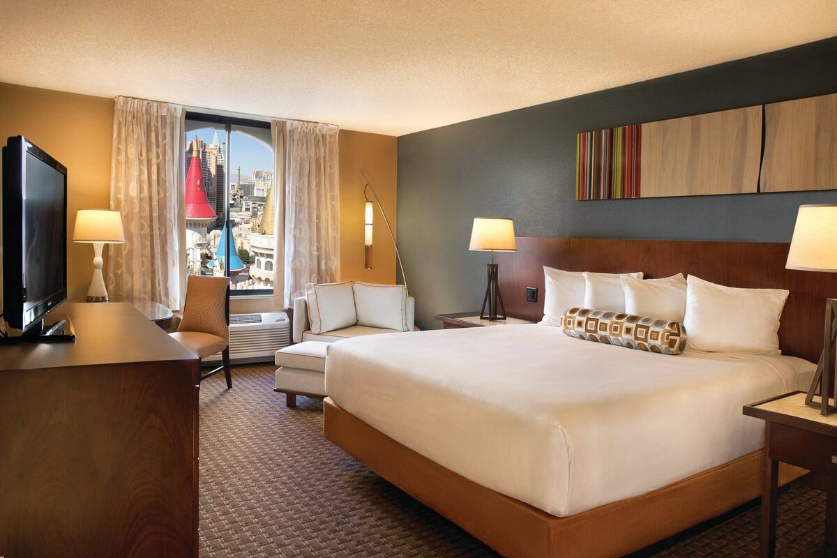 Een hotelkamer met een groot bed, een bureau, een stoel en een televisie.