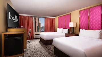 Habitación de hotel con dos camas, televisión, escritorio y ventana con vista a la ciudad.