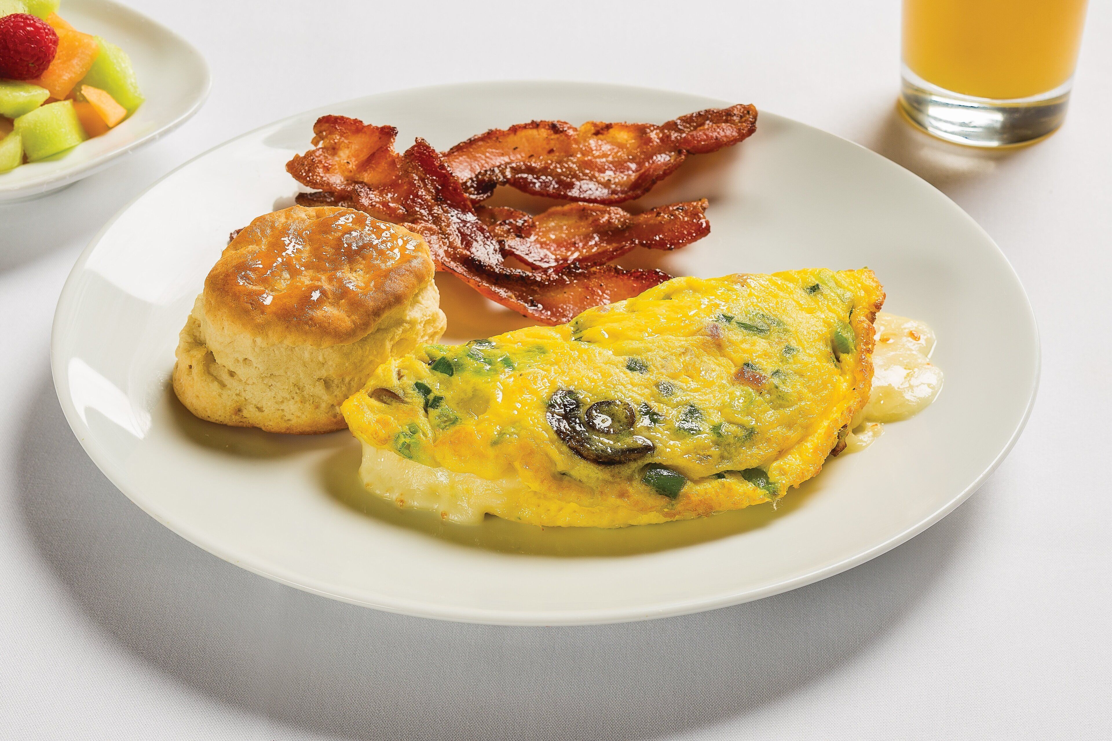 A plate with a breakfast of eggs, bacon, and a biscuit.