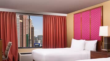 A hotel room with a large bed, a chair, a desk, and a view of tall buildings.