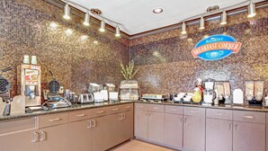 A breakfast counter with a mosaic backsplash, a Baymont Breakfast Corner sign, and various breakfast items and appliances. - Baymont by Wyndham Dallas/ Love Field (Dallas)