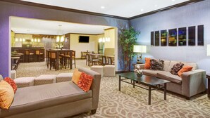 A hotel lobby with a seating area, a dining area, and a reception desk. - Baymont by Wyndham Dallas/ Love Field (Dallas)