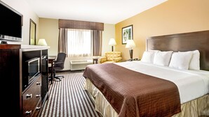 A hotel room with a large bed, a TV, a desk, and a chair. - Baymont by Wyndham Dallas/ Love Field (Dallas)