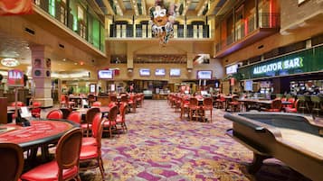 Experience the excitement of gaming at this vibrant casino, featuring a variety of tables and chairs, a balcony with a railing, and a restaurant.