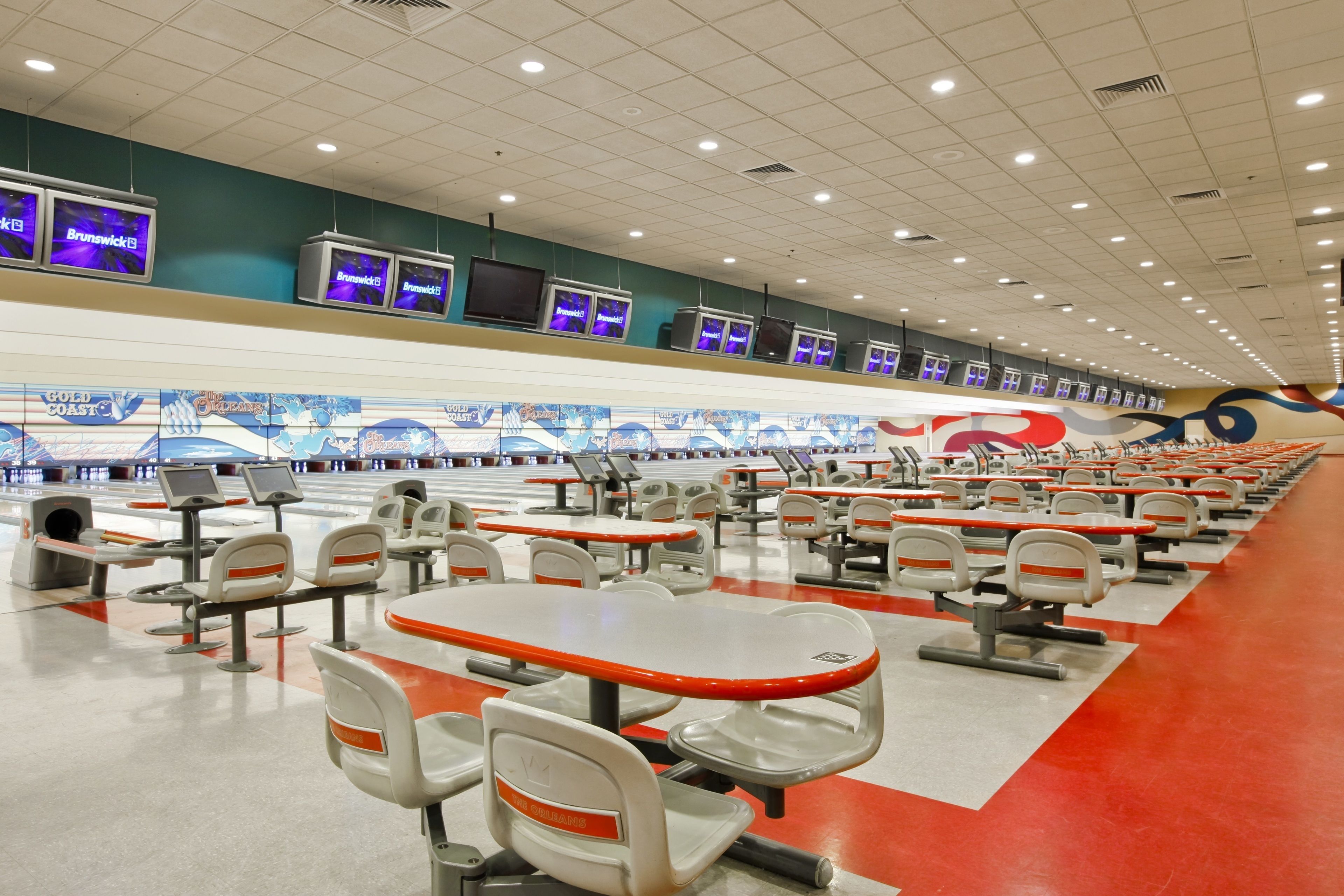 Un bowling doté de nombreuses pistes, d’espaces pour s’asseoir et d’écrans placés au-dessus des pistes qui affichent les scores.