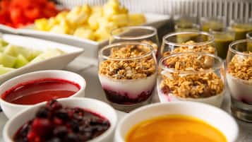 A variety of food items including bowls of fruit, granola, and different types of sauces.