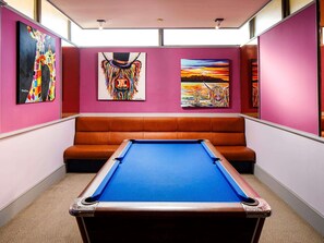 A pool table in a room with a brown leather bench, pink walls, and three artworks. - Mercure Ayr Hotel (Ayr)