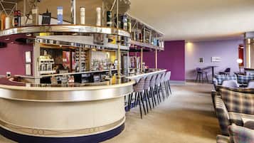 A bar area with a curved counter, multiple seating options, and a variety of bottles and glasses.