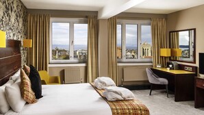 A hotel room with a bed, a desk, a chair, a radiator, and a view of the cityscape. - Mercure Ayr Hotel (Ayr)