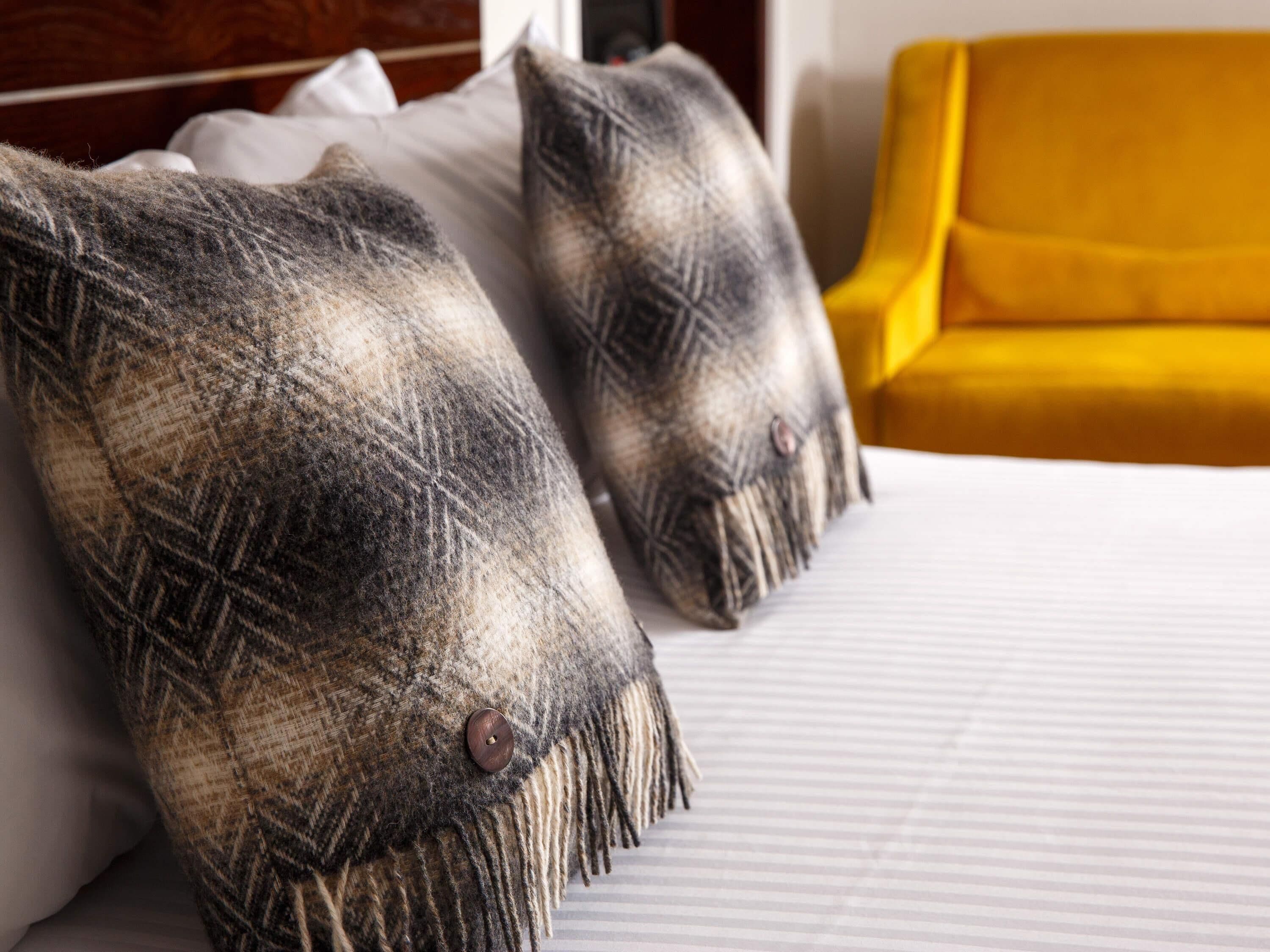 Una cama con dos almohadas y una silla amarilla.