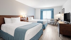 A hotel room with two beds, a desk with a computer, a TV, and a window with curtains. - Ramada by Wyndham Surrey/Langley (Surrey)