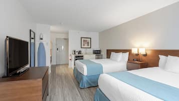 Habitación de hotel con dos camas, televisión, escritorio y kitchenette.