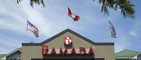 A building with the sign "RAMADA" and three flags on top.