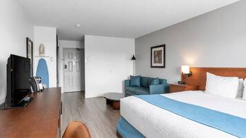 A hotel room with a bed, a desk, a television, a sofa, and a coffee table.