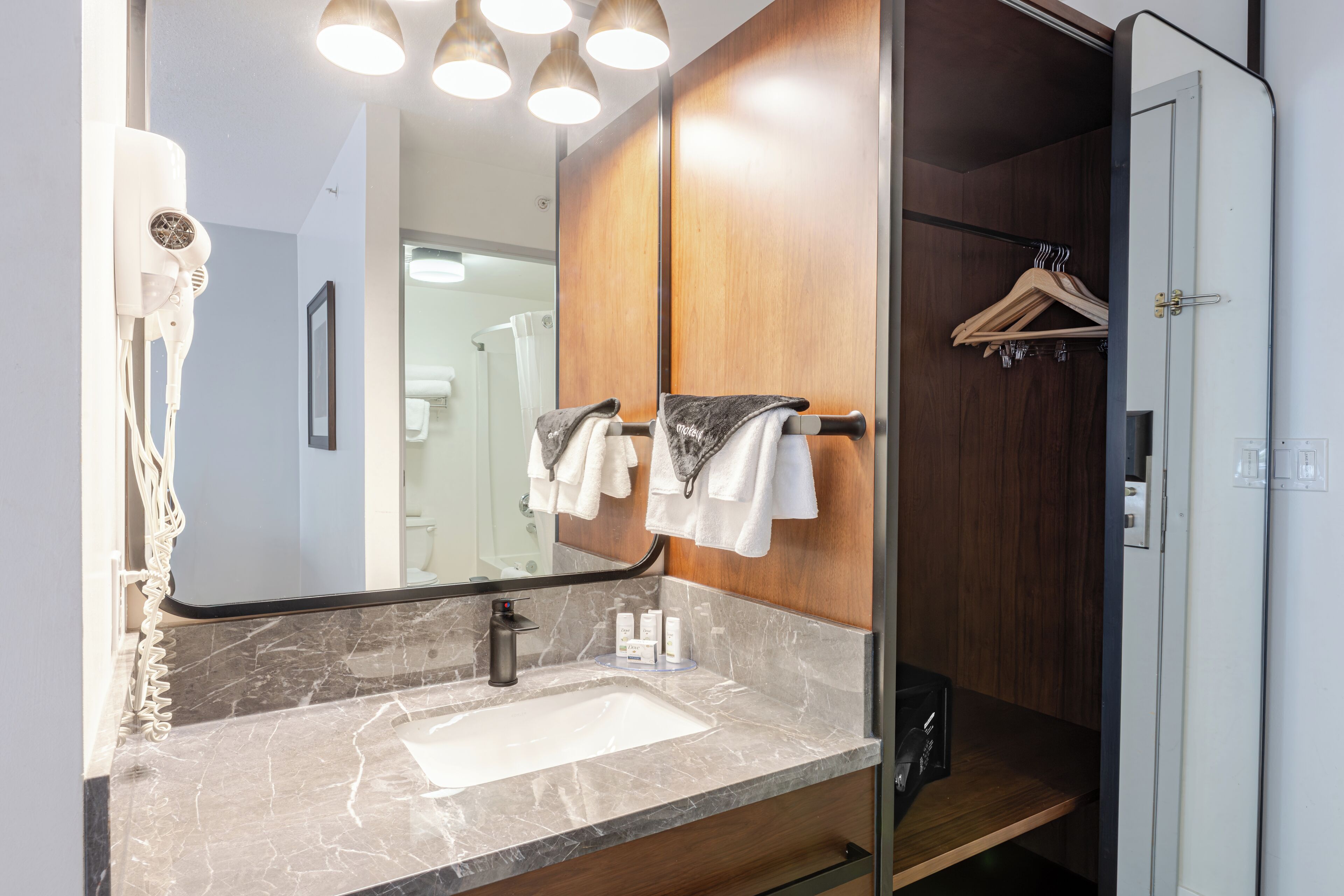 A bathroom with a marble sink, a large mirror, and a wooden vanity.