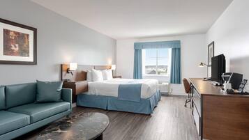 Una habitación de hotel con cama, escritorio, sofá y ventana con cortinas.