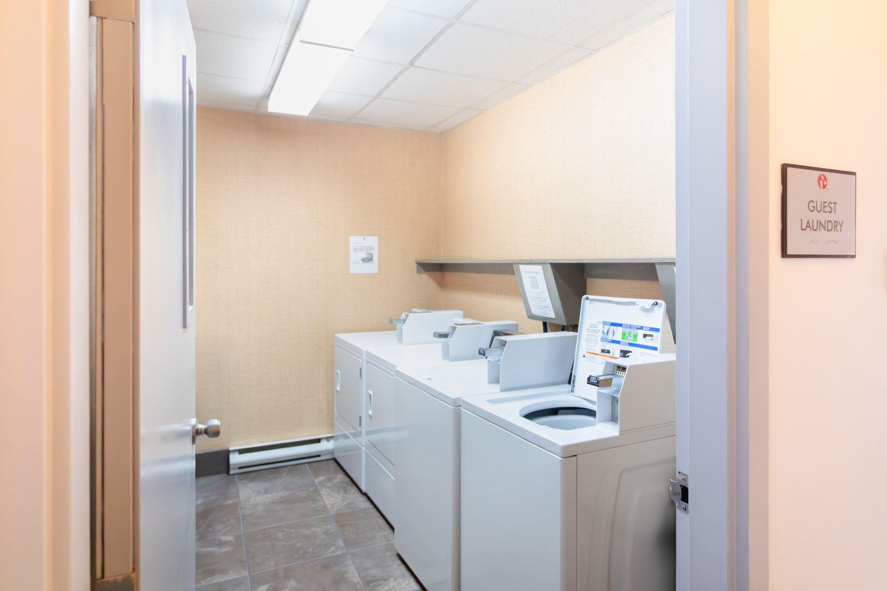 A laundry room with a sign indicating it's for guests, a washing machine, and a dryer.
