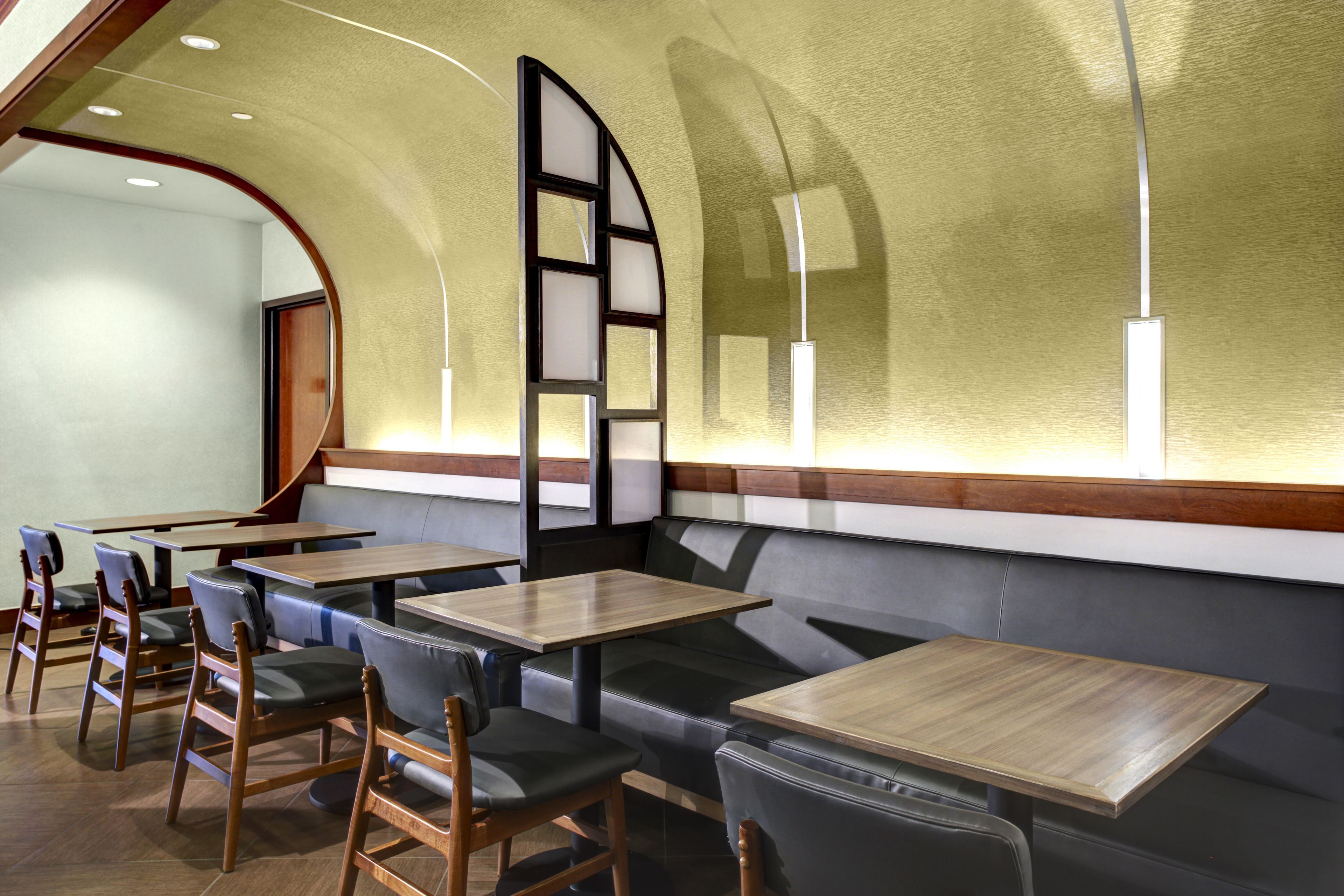 Un interno di ristorante con posti a sedere in cabina, tavoli in legno e soffitto a volta.