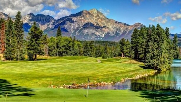 A golf course with a pond, surrounded by trees and mountains. - Best Western Mountainview Inn (Golden)