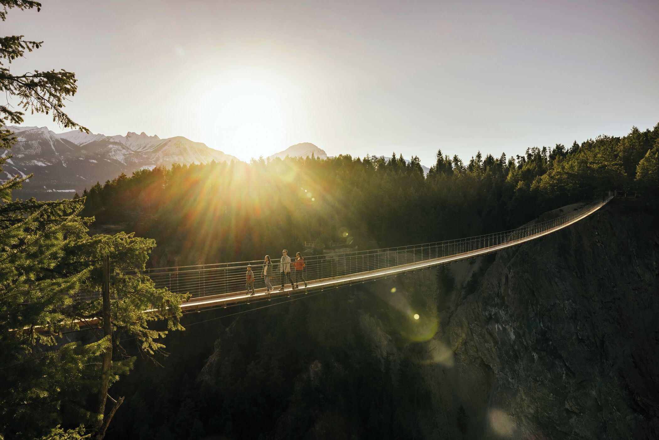 A suspension bridge with a mountainous backdrop and a clear sky.