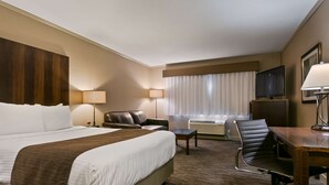 A hotel room with a large bed, a desk, a chair, a television, and a window with curtains. - Best Western Mountainview Inn (Golden)