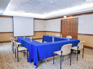 Conference room with a long table and six chairs, a whiteboard, and a door with a glass panel.