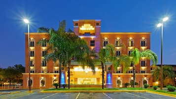Hotel features a central entrance with a canopy and stairs, flanked by two wings with balconies on each floor.