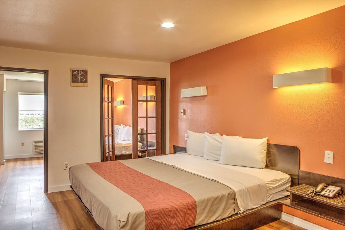 A hotel room with a bed, bedside table, and a wall-mounted phone.