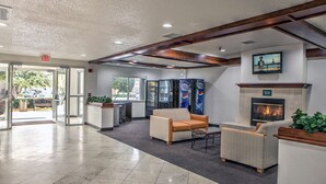 A lobby with a fireplace, seating area, and a reception desk. - Motel 6 Dallas, TX - Northwest (Dallas)