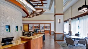 A hotel lobby with a curved reception desk, a bar area, and seating with a view of the city. - Hyatt Place Memphis/Wolfchase Galleria (Memphis)