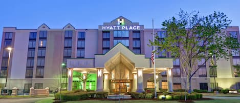 A multi-story hotel with a prominent entrance, a flag, and a well-maintained lawn.