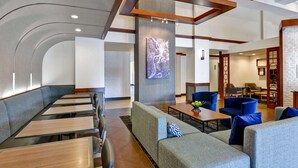A modern hotel lobby with a curved seating area, a reception desk, and a wall-mounted TV. - Hyatt Place Memphis/Wolfchase Galleria (Memphis)