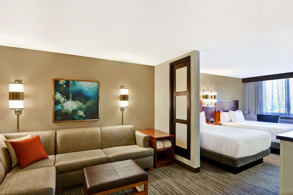 Une chambre d’hôtel avec un canapé, une petite table, un lit et un tableau au mur.