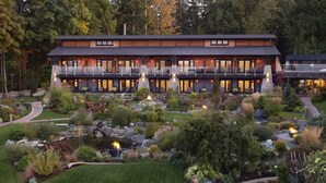 A two-story lodge with a stone facade, outdoor seating, and a pond. - Kingfisher Pacific Resort and Spa (Courtenay)
