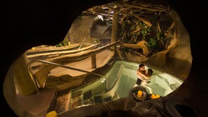 A hot tub with a wooden structure and a stone wall. - Kingfisher Pacific Resort and Spa (Courtenay)