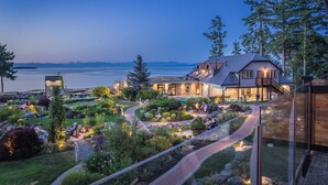 A large house with a landscaped garden, a pool, and a view of the water. - Kingfisher Pacific Resort and Spa (Courtenay)