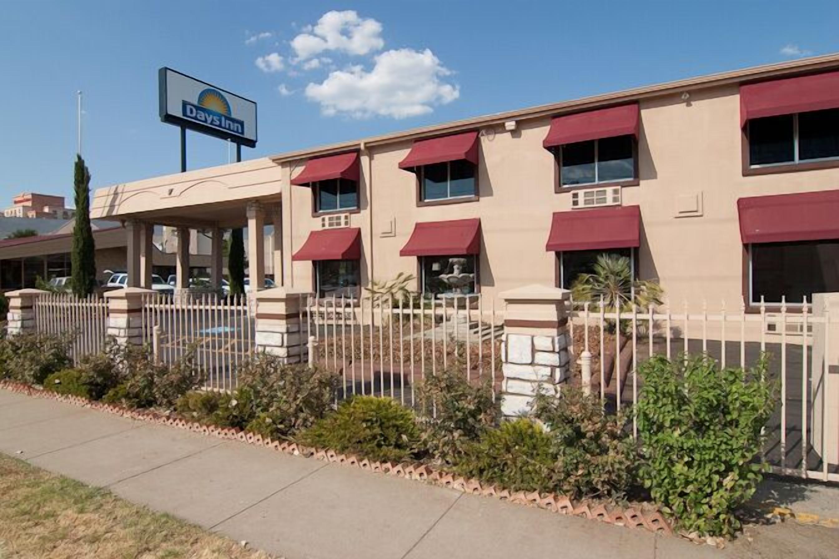 A Days Inn with a beige facade, red awnings, and a white fence.