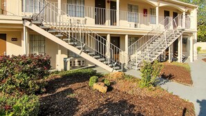 A two-story building with a central staircase, multiple balconies, and a landscaped front yard. - Days Inn by Wyndham Market Center Dallas Love Field (Dallas)