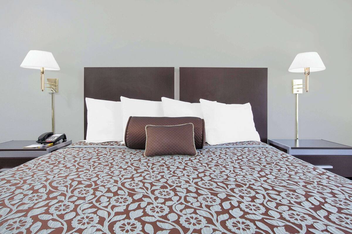 A hotel room with a large bed, two bedside tables, a telephone, and two wall-mounted lamps.