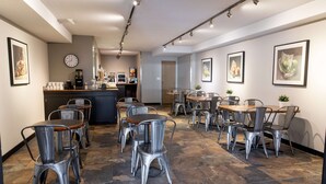 Un restaurante con sillas y mesas de metal, una máquina de café y cuadros en las paredes.