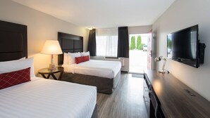 Una habitación de hotel con dos camas, televisor, escritorio y ventana con cortinas.