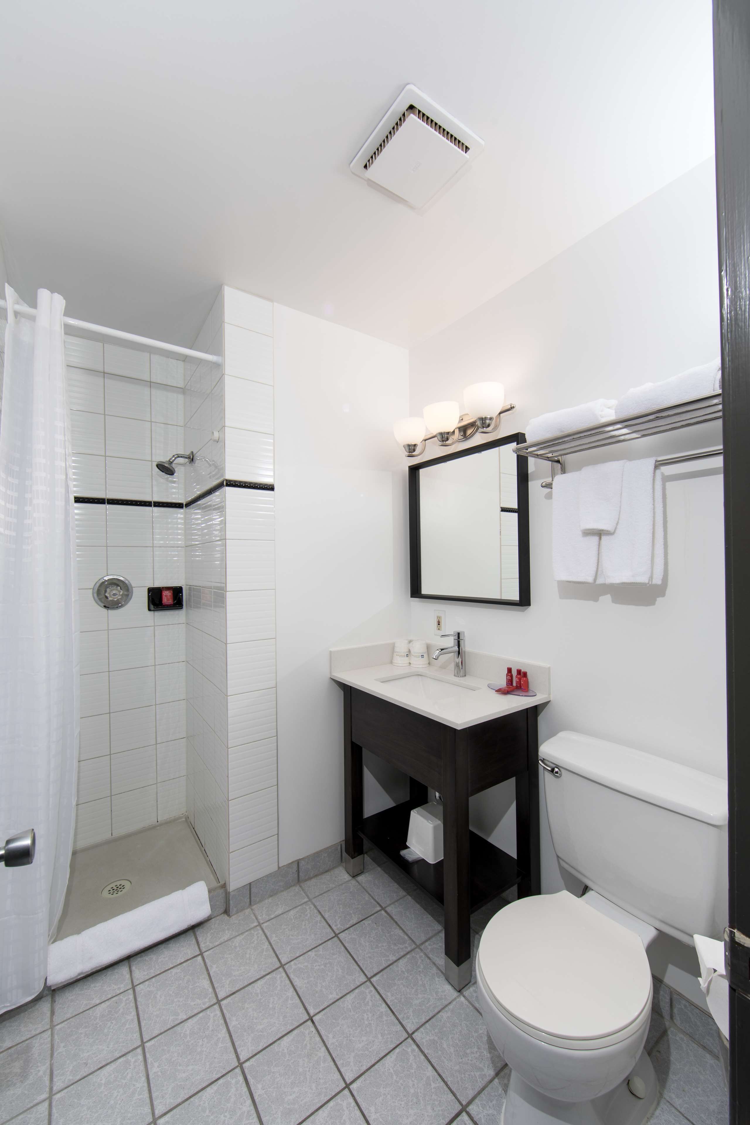 Une salle de bain équipée d’une douche, de toilettes, d’un lavabo et d’un miroir.